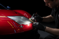 Professional headlight restoration on a racing red luxury sports car