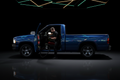 Technician performing interior vacuum and wipe-down on a 1990s Dodge Ram 1500 in a dark luxury detailing studio